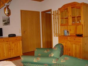a living room with a green couch and wooden cabinets at Pension Martens - Gaubenwohnung in Wieck