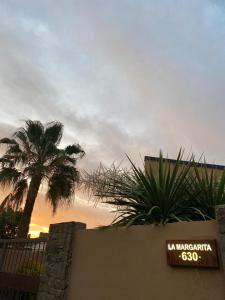 un panneau devant un bâtiment avec un palmier dans l'établissement Posada “LA MARGARITA”, à San Rafael