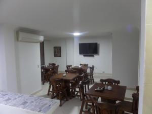 a dining room with tables and chairs and a flat screen tv at Aparta Hotel Plaza Real Norte in Cali
