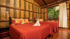 two beds in a room with wooden walls at Orquideas Boutique Hotel in Fortuna