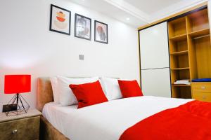 um quarto com uma cama com almofadas vermelhas e brancas em Elite Luxury Apartments Kilimani - An Oasis of Serenity and Tranquility em Nairobi