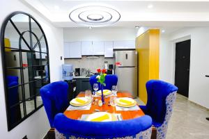 a dining room table with blue chairs and a kitchen at Elite Luxury Apartments Kilimani - An Oasis of Serenity and Tranquility in Nairobi