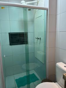 La salle de bains est pourvue d'une douche en verre et de toilettes. dans l'établissement Muro Alto Condominio Clube Apt.111 térreo, à Porto de Galinhas
