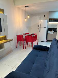 - un salon avec un canapé bleu et une table avec des chaises rouges dans l'établissement Muro Alto Condominio Clube Apt.111 térreo, à Porto de Galinhas