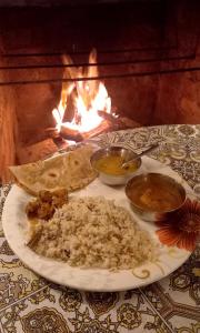 a plate of food on a table in front of a fire at Coorg Coffee Park Farmstay in Somvārpet