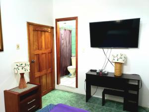 ein Wohnzimmer mit einem TV und einem Tisch mit einem Schreibtisch sidx sidx in der Unterkunft EMMA HOUSE in Puerto Baquerizo Moreno