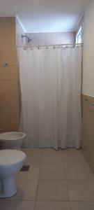 y baño con cortina de ducha blanca y aseo. en Alojamientos Litoral - 3 B en Gualeguaychú