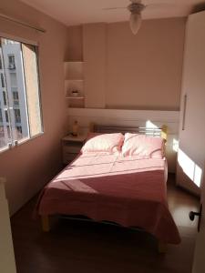 1 dormitorio con cama con sábanas rosas y ventana en Ensolarado e espaçoso quarto/sala no coração de POA, en Porto Alegre