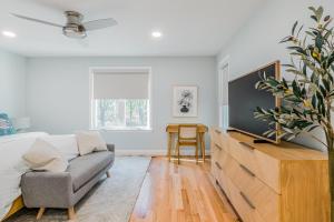 a white bedroom with a couch and a dresser at Peace Among the Pines in Wellfleet