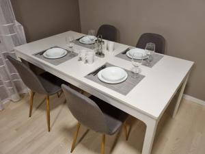 uma mesa branca com cadeiras, pratos e copos de vinho em Chausseen Apartment 