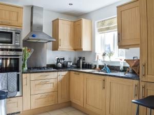 a kitchen with wooden cabinets and a stove at Lime Court in Leatherhead
