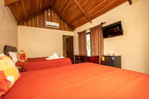 a hotel room with two beds and a tv at Orquideas Boutique Hotel in Fortuna