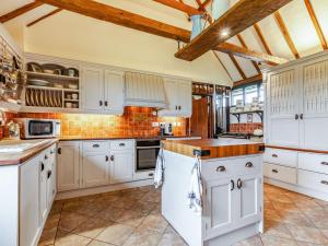 a kitchen with white cabinets and a brick wall at Flint Barn in Doddington