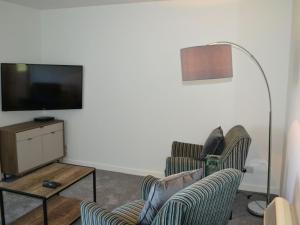 a living room with two chairs and a flat screen tv at The Cottage 47 in Aird Tong