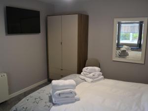 a room with a bed with white towels on it at The Cottage 47 in Aird Tong