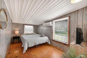 a bedroom with a bed and a television in it at Shipwrecked Shack Waterfront House Boat on Land in Sealevel