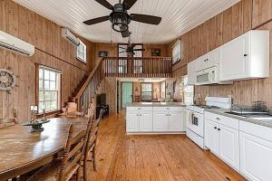 a large kitchen with a table and a ceiling fan at Shipwrecked Shack Waterfront House Boat on Land in Sealevel