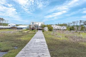 a wooden boardwalk leading to a house on the beach at Shipwrecked Shack Waterfront House Boat on Land in Sealevel