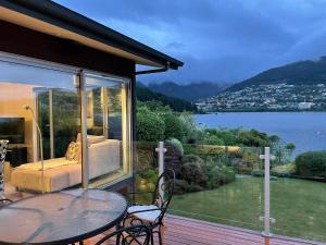 a patio with a table and a view of the water at Peninsular Lakefront in Queenstown