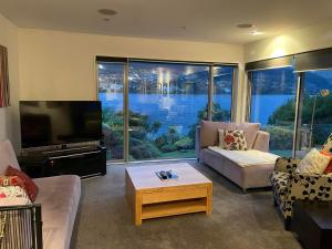 a living room with a couch and a tv at Peninsular Lakefront in Queenstown