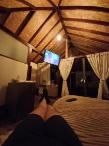 uma pessoa deitada numa cama a ver uma televisão em LoMar Sol&Luna em Sasaima