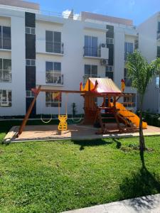 a playground in a yard in front of a building at Departamento 2 habitaciones vista a la alberca Nube by EITA in Cancún