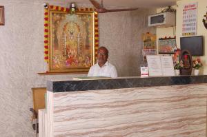 um homem parado atrás de um balcão num templo em Adhi Residency em Kanchipuram