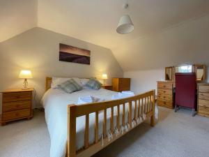 ein Schlafzimmer mit einem großen Bett und einem Kinderbett aus Holz in der Unterkunft Milton Cottage in Invercassley