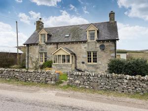 ein altes Steinhaus mit einer Steinmauer in der Unterkunft Milton Cottage in Invercassley