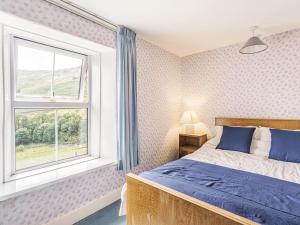 una camera con un letto blu e una finestra di High Rake a Glenridding
