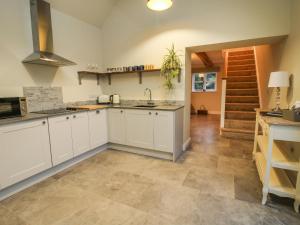 uma cozinha com armários brancos, pisos em azulejo e uma escadaria em The Barn em Shrewsbury
