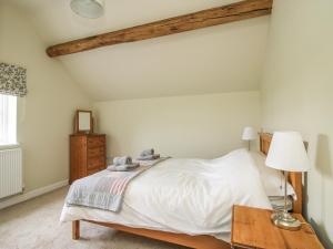 um quarto com uma cama branca e uma mesa em The Barn em Shrewsbury