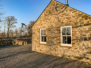 a stone building with two windows on the side of it at Newonstead Bothy in Kirkharle