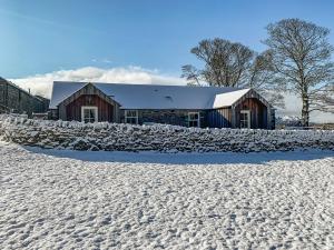 a barn in the snow with a stone wall at Newonstead Bothy in Kirkharle