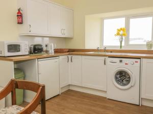 a kitchen with white cabinets and a washing machine at Lantonhall West Wing in Lanton