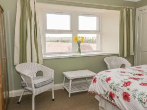 a bedroom with a bed and two chairs and a window at Lantonhall West Wing in Lanton