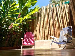 two lawn chairs sitting next to a wooden fence at Chalés Água Grande in Maresias