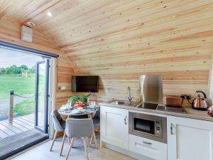 a kitchen with a table in a tiny house at Chestnut-uk36261 in Llanfair Caereinion
