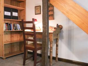 a wooden desk with a chair next to a book shelf at Clematis Cottage in Penrith