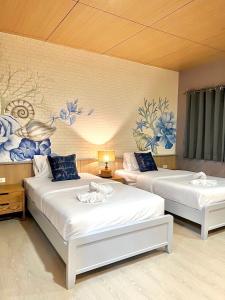 2 Betten in einem Zimmer mit blauen Blumen an der Wand in der Unterkunft Phi Phi Indigo Hotel in Ko Phi Phi