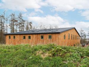 a wooden barn with a black roof on a field at Sika Cottage - Uk36194 in Fordingbridge