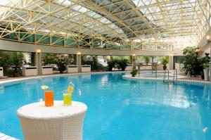 een groot zwembad met twee drankjes op een tafel bij Jianguo Hotspring Hotel in Beijing