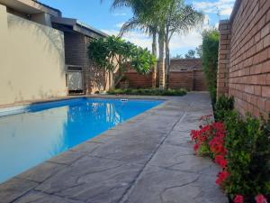 a swimming pool in a backyard with a brick wall at Alucarni Guest House with solar energy in Upington