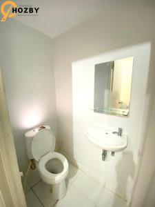 een witte badkamer met een toilet en een wastafel bij Hozby Suites Aeropolis Premier in Teko