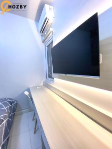 een grote flatscreen-tv aan een muur in een kamer bij Hozby Suites Aeropolis Premier in Teko
