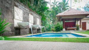 a swimming pool next to a building with a gazebo at Lotus Residence Tabanan in Tabanan