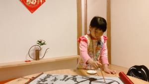 Uma jovem a cortar um bolo com uma faca. em Akitsuki Kominka Ryokan You em Asakura