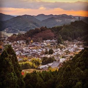 małe miasteczko w środku doliny z górami w obiekcie Akitsuki Kominka Ryokan You w mieście Asakura