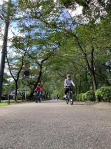 dwoje ludzi jeżdżących rowerami po drodze w parku w obiekcie Akitsuki Kominka Ryokan You w mieście Asakura