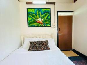 una camera da letto con un letto bianco con un dipinto sul muro di Blissful Cottage a Pantai Cenang